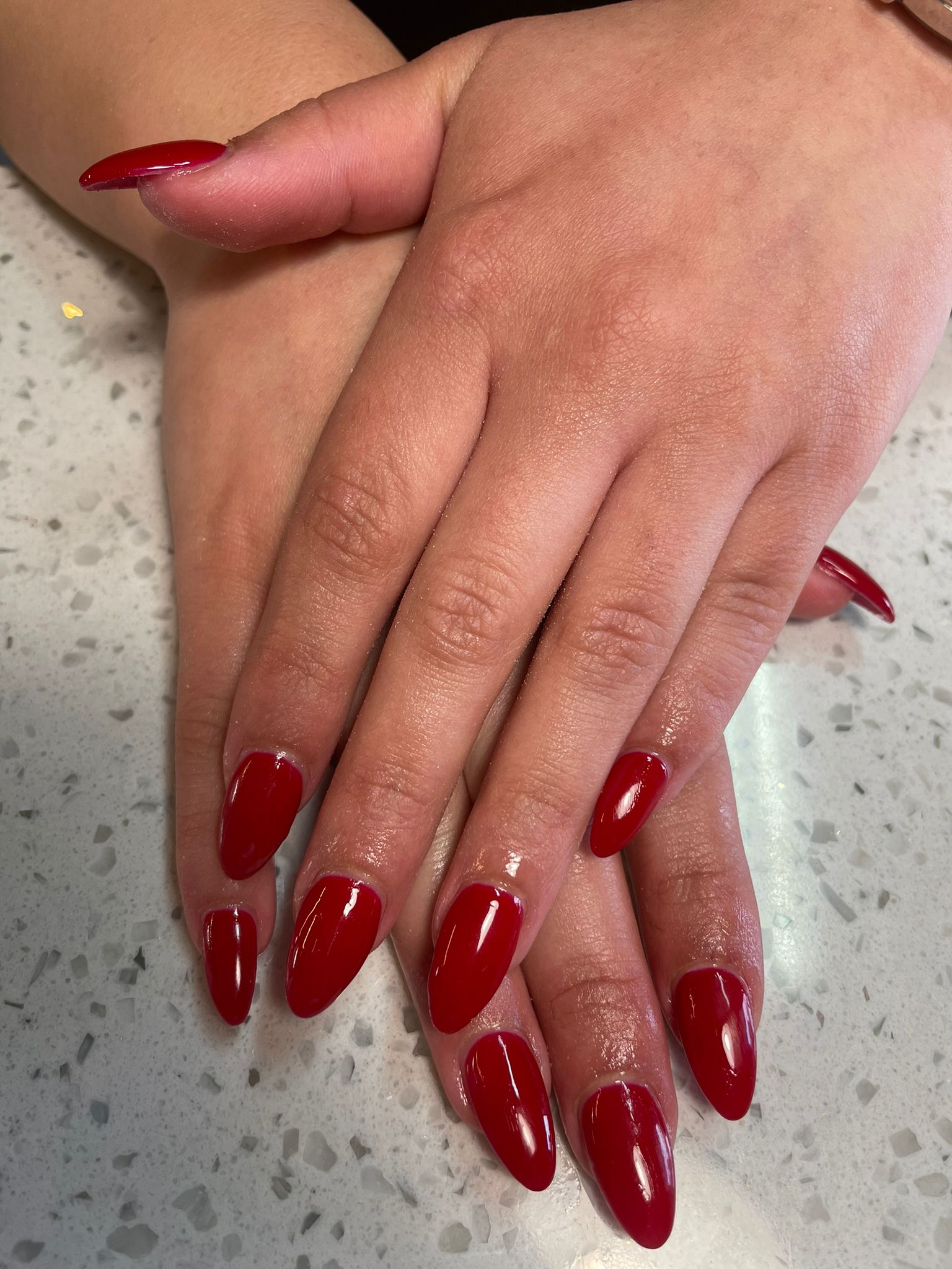 Dieprode nagels in amandelvorm op de terrazzo balie